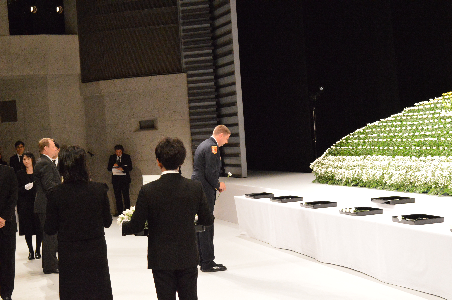 追悼式で献花するスキマホーン氏（写真中央）
