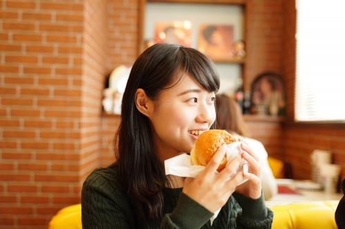 ハンバーガーを頬張る女性の写真