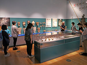 土器などの展示物の前で説明を聞く教員達の様子