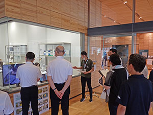 展示物をガラス越しに見ながら説明を聞く教員達の様子