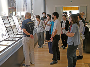 複数の箱に収められた展示物を見ながら説明を聞く教員達の様子